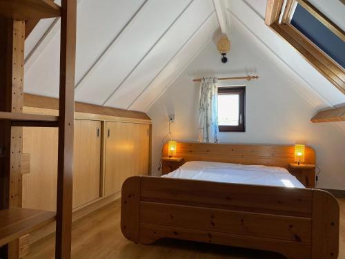 a bedroom with a wooden bed in a attic at Zeegalm Bungalows in Middelkerke
