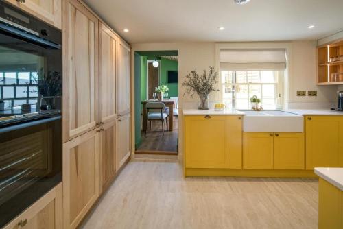 a large kitchen with yellow cabinets and a table at Honeybee Cottage in Cowes