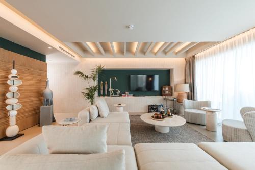 a living room with white furniture and a tv at Folie Marine Hotel & Beach Club in Jal