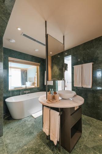 a large bathroom with a tub and a sink at Folie Marine Hotel & Beach Club in Jal