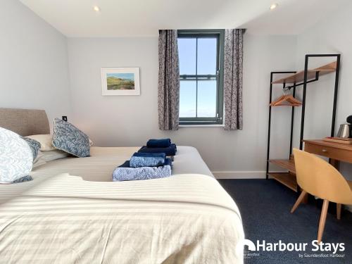 a bedroom with a bed and a desk and a window at Harbour Stays at Ocean Square in Saundersfoot