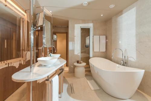a bathroom with two sinks and a tub and a toilet at Folie Marine Hotel & Beach Club in Jal