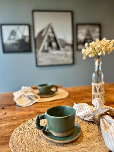 a wooden table with a green cup and a vase with flowers at Alpinada Cabanas in Carlos Barbosa