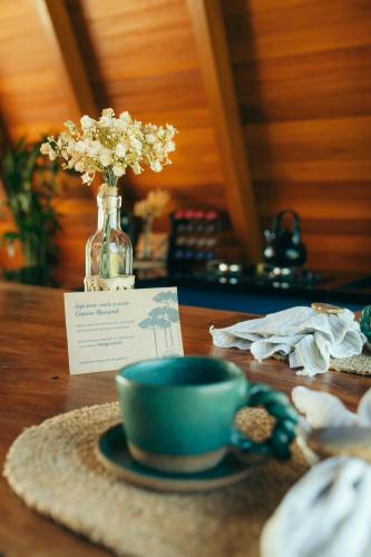 a table with a blue cup and a vase of flowers at Alpinada Cabanas in Carlos Barbosa