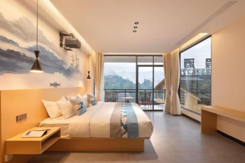 a bedroom with a large bed and a large window at Scenoria Longji Inn in Heping