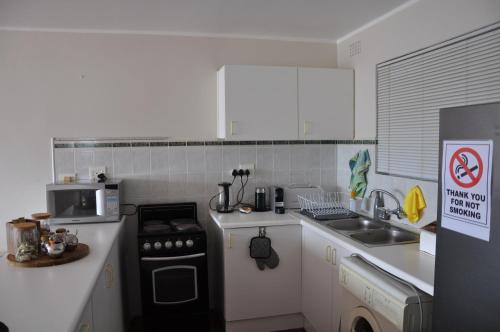 a small kitchen with a stove and a microwave at Suite at Bay in Mossel Bay