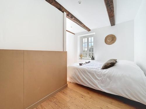 a white bedroom with a bed and a large window at Bienvenue au Gîte Cassa in Jullouville-les-Pins