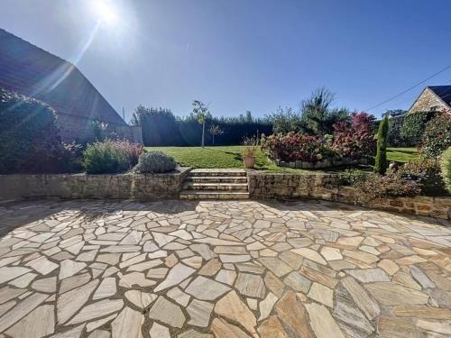 a stone patio with a stone wall and a garden at Bienvenue au Gîte Cassa in Jullouville-les-Pins
