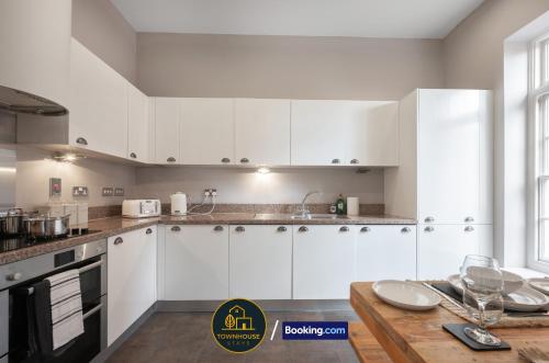 eine Küche mit weißen Schränken und einem Holztisch in der Unterkunft 4BR Contractor House by Townhouse Stays, Short Lets & Serviced Accommodation in Colchester Free Parking, Garden & WiFi in Lexden