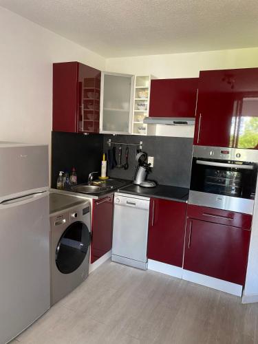 une cuisine avec des armoires et des appareils rouges et blancs dans l'établissement Charmant studio cabine sur le port de Carnon-Plage, à Mauguio