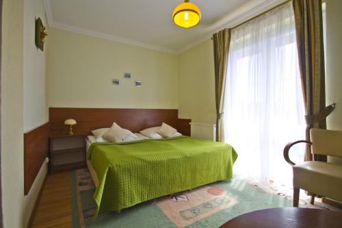 a bedroom with a green bed and a large window at Villa Tropikana in Łeba