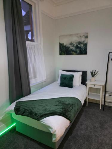 a bedroom with a green and white bed with a window at Spacious - 8ight Havens Folkestone in Folkestone