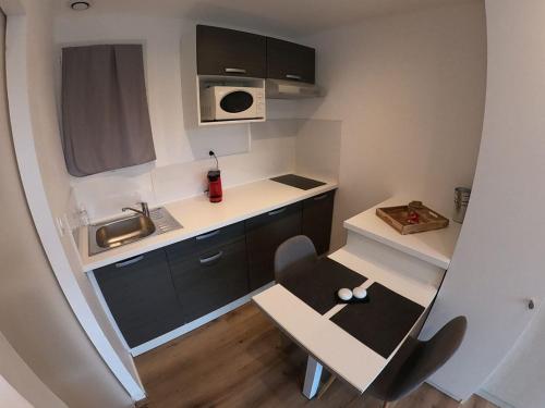 une petite cuisine avec une petite table et un évier dans l'établissement La villa baie du lac les pins, à Biscarrosse
