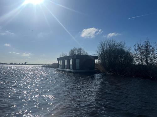 a house on a boat on a body of water at Surla Houseboat "Walvis" Kagerplassen in Buitenkaag