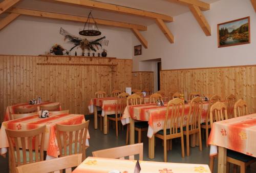 restauracja z drewnianymi ścianami, stołami i krzesłami w obiekcie Penzion Rakovec w mieście Bukovinka
