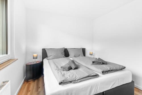 a white bedroom with a large bed with white sheets at 24-7 Living - Lüdinghausen Apartments in Lüdinghausen