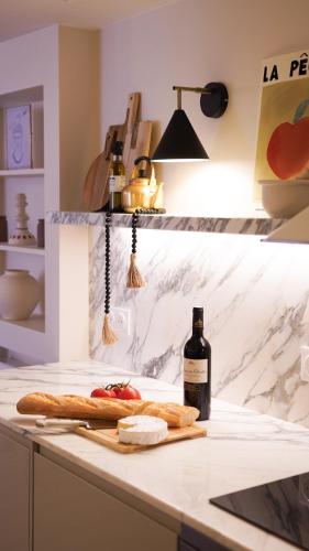 - une bouteille de vin assise sur un comptoir de cuisine avec une table avec du pain et du fromage dans l'établissement VENDOME Parisian elegance with a patio, à Paris