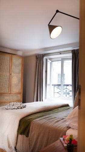 une chambre avec un grand lit et une fenêtre dans l'établissement VENDOME Parisian elegance with a patio, à Paris