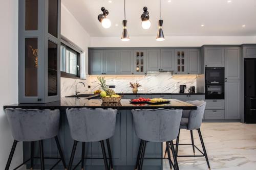 a kitchen with gray cabinets and a island with bar stools at Villa Llaha Gabrijela - Luxurious Private Escape with Pool in Nature - By Villa Mana Gers in Gaïtánion