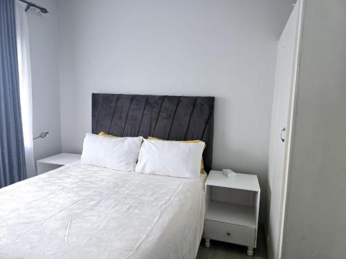 a bedroom with a white bed with a wooden headboard at Casamaya Avondale Harare - Sleeps 6 with Parking in Harare
