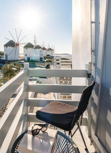 a chair sitting on a balcony with a windmill at Sunset Windmills House in Mýkonos City