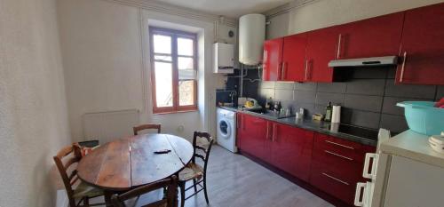une cuisine avec une table en bois et des placards rouges dans l'établissement Appartement Le Belvédère, à Lalouvesc