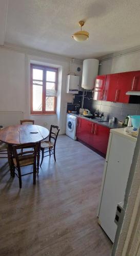 une cuisine avec des armoires rouges et une table et des chaises dans l'établissement Appartement Le Belvédère, à Lalouvesc