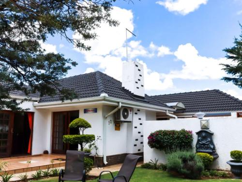 a white house with chairs in the yard at The Star Guest House in Witbank