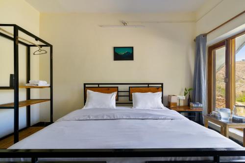 a bedroom with a large bed with white sheets at Himkosi Farm by the River in Almora