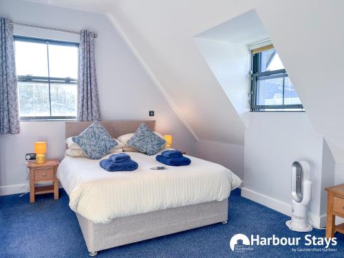 a bedroom with a bed with blue towels on it at Harbour Stays at Ocean Square in Saundersfoot