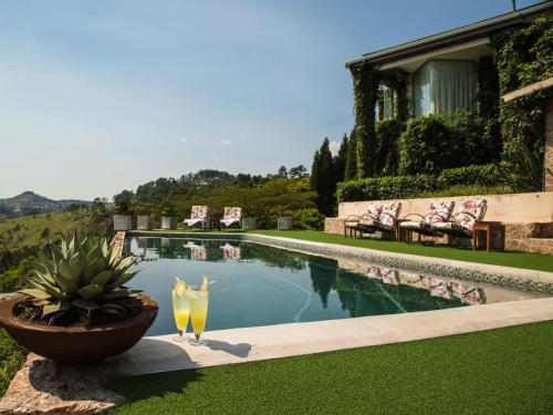 a pool with two drinks sitting next to a house at Ematjeni Retreat & Guesthouse in Mbabane