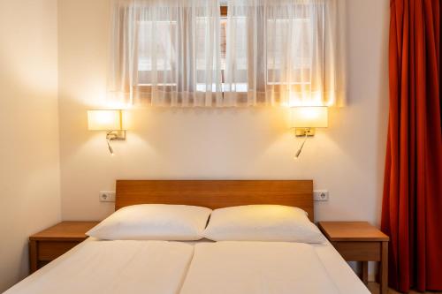 a bedroom with a bed with two lamps and a window at St. Ulrichhof in Lana