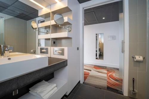 ein Badezimmer mit Waschbecken und Spiegel in der Unterkunft Fletcher Wellness-Hotel Helmond in Helmond