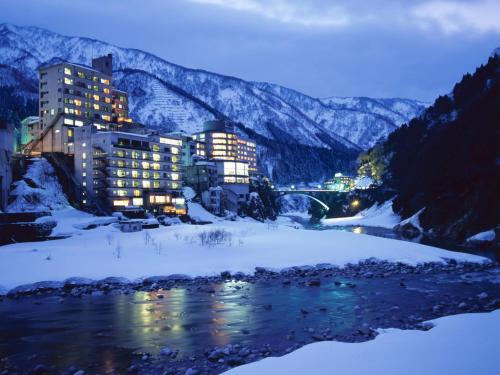 a city in the snow next to a river at Entaijiso in Kurobe