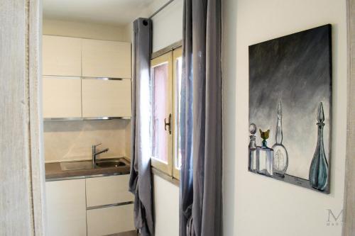 a kitchen with white cabinets and a sink and a window at Trilocale sul Lungomare in Cannigione