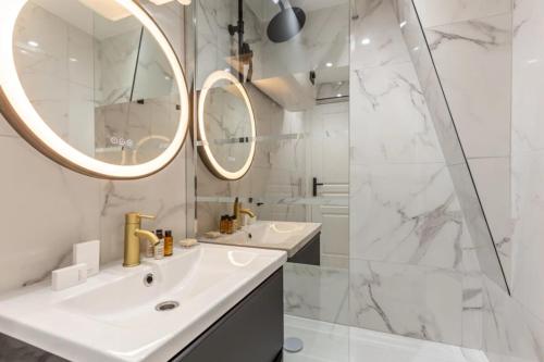 une salle de bain blanche avec deux lavabos et un miroir dans l'établissement 21#Opera#Louvre#Paris02#2bedrooms#AC, à Paris