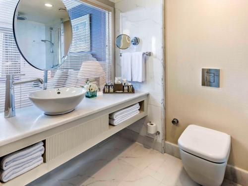 a bathroom with a sink and a toilet and a mirror at Rixos Downtown Antalya - The Land Of Legends Access in Antalya