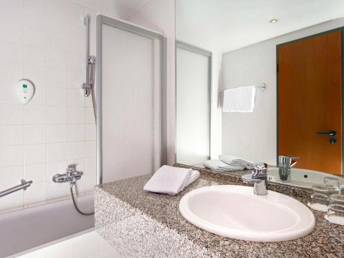 bagno con lavandino, doccia e specchio di Congress Hotel Weimar by Mercure a Weimar