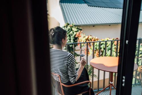 a woman sitting at a table on a balcony at Schmidtburger Hof in Weiler
