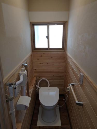 a small bathroom with a toilet and a window at Hermit 知床 in Shari