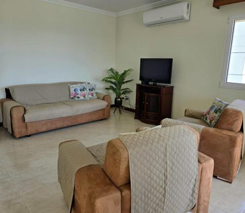 a living room with couches and a flat screen tv at Ocean Breeze in Ponta Delgada