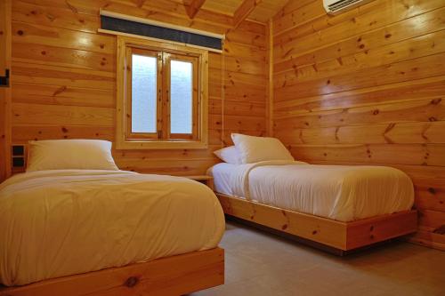 two beds in a log cabin with a window at أكواخ البرنسيسة in Jeddah