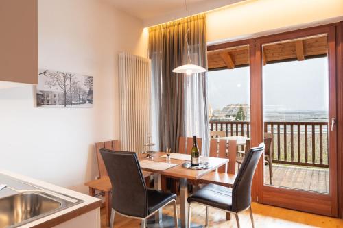 a dining room with a table and chairs and a balcony at St. Ulrichhof in Lana