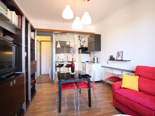 un salon avec un canapé rouge et une table dans l'établissement Appartement T2 avec wifi à La Bourboule, proche thermes, jusqu'à 4 personnes - FR-1-608-285, à La Bourboule