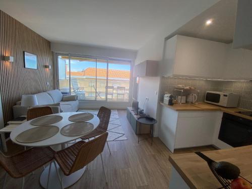 une cuisine et un salon avec une table et des chaises dans l'établissement Appartement T1 avec Terrasse et Parking Sécurisé - FR-1-374-234, à Arcachon