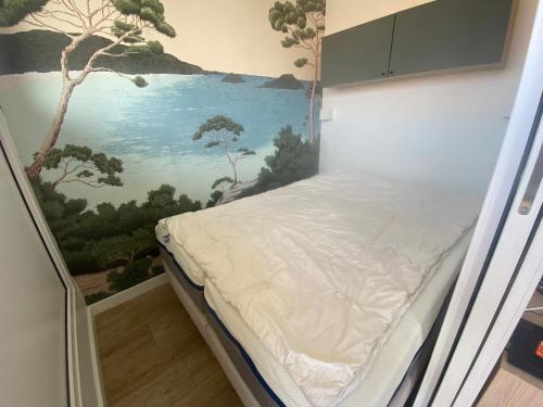 un lit dans une chambre avec un tableau sur le mur dans l'établissement Appartement T1 avec Terrasse et Parking Sécurisé - FR-1-374-234, à Arcachon