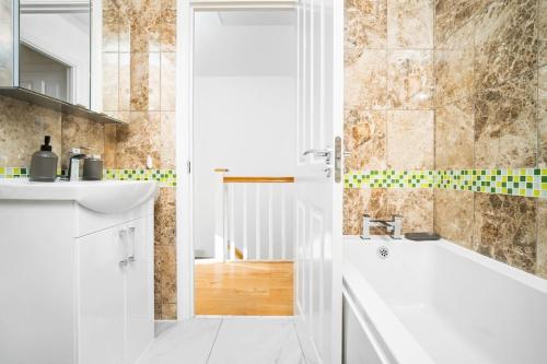 a white bathroom with a tub and a sink at Spacious, Chic Townhouse with Parking & Garden in Birmingham