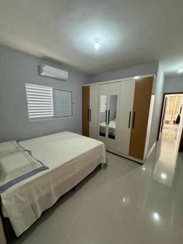 une chambre avec un grand lit et une armoire dans l'établissement Casa em Itanhaém com Piscina e Ar condicionado à 900 Metros da Praia, à Itanhaém