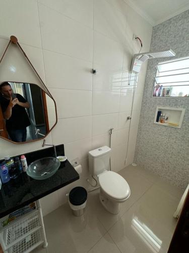une personne prenant une photo d'une salle de bains avec toilettes dans l'établissement Casa em Itanhaém com Piscina e Ar condicionado à 900 Metros da Praia, à Itanhaém