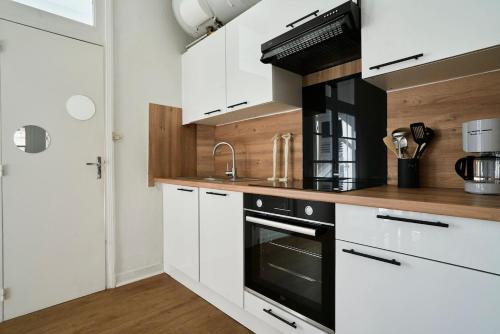 une cuisine avec des armoires blanches et un four noir dans l'établissement Élégant T2, charmant,, à Lambersart
